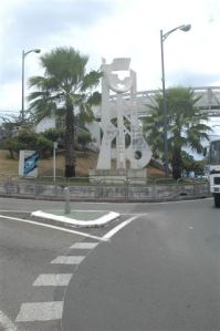 arbres, poteaux électriques, panneau publicitaire empêche la lecture de l'oeuvre